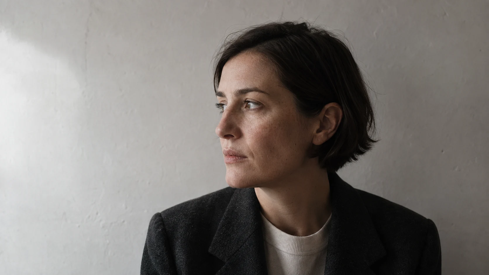 Window-lit portrait of a fictional woman with short dark hair and natural skin texture, an AI-generated study